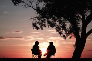 silhouette of two people in retirement sitting on a  chair near tree from investing in a self-directed IRA